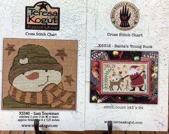 May include: Two Teresa Kogut cross stitch charts. The left chart, XS140 Sam Snowman, shows a snowman in a green hat and plaid scarf. The right chart, XS312 Santa's Young Buck, depicts Santa with a reindeer and the text DEC 25.