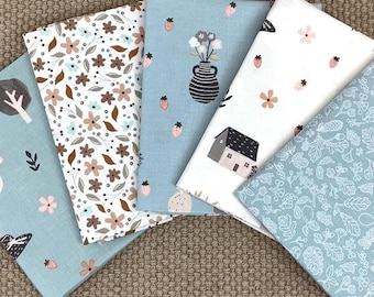 May include: Five folded fabric swatches featuring various patterns including brown and pink flowers, strawberries, a dark vase with flowers, a small house, and white botanical line art on a light blue background.