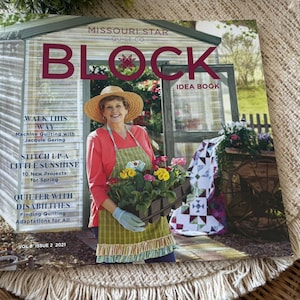 May include: A magazine cover for Missouri Star Quilt Co.'s Block Idea Book. The cover features a woman in a straw hat and apron holding a flower box. Text includes "Walk This Way," "Stitch Up a Little Sunshine," and "Quilter with Disabilities." The magazine is Vol. 8, Issue 2, 2021.