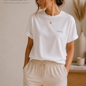 Könnte beinhalten: Weißes T-Shirt mit hochgekrempelten Ärmeln und dem schwarzen Aufdruck "Vita Lenta". Das Model trägt eine beige Jogginghose. Der Markenname "SORELLAN" und der Text "MINIMAL FASHION & LIFESTYLE ESSENTIALS" befinden sich oben links.