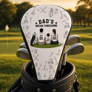 Könnte beinhalten: Ein weißer Golfschlägerhaube mit einem schwarzen Linienmuster aus Golfausrüstung und einer zentralen Illustration einer dreiköpfigen Familie auf Gras. Der Text lautet DAD'S DREAM THREESOME, wobei die Figuren als DAD 01, LEO 07 und MOM 02 beschriftet sind.