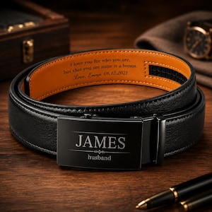 Może przedstawiać: Czarny skórzany pasek z personalizowaną klamrą. Klamra jest wygrawerowana z imieniem "JAMES" i słowem "husband" poniżej. Wnętrze paska ma pomarańczową podszewkę z nadrukowaną wiadomością. Stylowy dodatek.