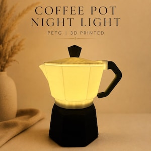 May include: A 3D printed PETG coffee pot night light with a black base, handle, and lid knob. The upper chamber glows with a warm light. The text COFFEE POT NIGHT LIGHT PETG | 3D PRINTED is displayed above the object in a dark brown font.