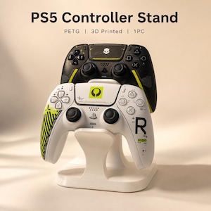 May include: A white 3D printed PETG stand for PS5 controllers. The stand holds two game controllers, one black with yellow accents and one white with black and yellow graphics. Text at the top reads PS5 Controller Stand, PETG, 3D Printed, 1PC.