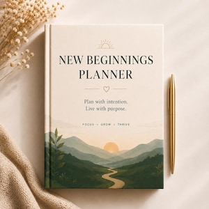 May include: A hardback planner with a cream-coloured cover featuring a landscape illustration of green mountains, a winding path, and a rising sun. The text reads: NEW BEGINNINGS PLANNER, Plan with intention. Live with purpose. FOCUS • GROW • THRIVE.