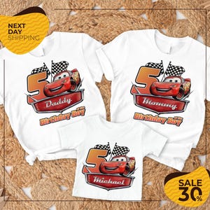 a collection of white t-shirts featuring the character Lightning McQueen from the Cars movie, along with the text "Daddy Birthday Boy" and "Michael Birthday Boy". The t-shirts are arranged on a textured background, and there is a yellow banner with the text "NEXT DAY SHIPPING" and a sale offer of "SALE 30%".