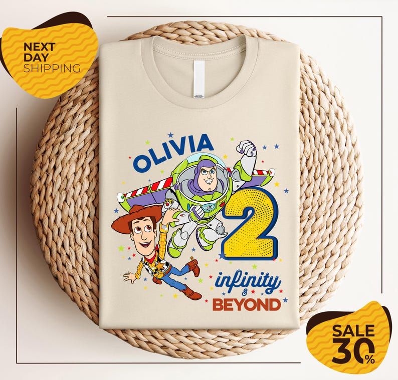 a t-shirt with a cartoon character from the Toy Story franchise, specifically Woody, and the text "Olivia 2 Infinity Beyond". The t-shirt is displayed on a woven basket, and there are two yellow price tags in the image.