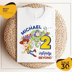 A white t-shirt with a graphic design featuring characters from the Toy Story franchise, specifically Buzz Lightyear and Woody, along with the text "Michael 2 infinity beyond". The t-shirt is displayed on a woven placemat, and there are yellow price tags with text indicating a sale of 30% off.