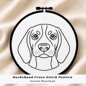 Può includere: Un motivo a punto croce in bianco e nero del muso di un cane, incorniciato in un telaio da ricamo nero. Il disegno presenta gli occhi, il naso e le orecchie del cane. Il testo in basso recita "Dachshund Cross Stitch Pattern Instant Download."