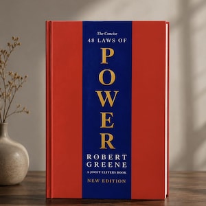May include: A hardcover book titled The Concise 48 Laws of Power by Robert Greene, a Joost Elffers book, New Edition. The cover features a vertical blue central band on a red background with gold lettering for the word POWER and white text.