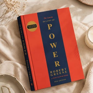 May include: The book titled The Concise 48 Laws of Power by Robert Greene features a vibrant red cover with a central navy blue vertical stripe. The title is printed in gold lettering, and a gold circular seal reads International Bestseller.