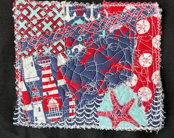 May include: A patchwork quilt square with a nautical theme. The square is made of various fabrics with different patterns, including lighthouses, anchors, seashells, and stars. The fabrics are in shades of blue, red, and white.