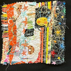 May include: A colorful patchwork quilt square with a variety of fabrics and textures. The square features a smiling yellow face, a star, and a variety of other designs. The square is surrounded by a black background.