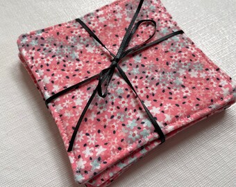 May include: Set of four pink and white floral fabric coasters tied together with a black ribbon.