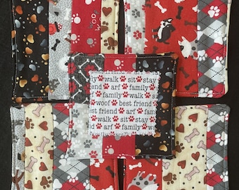 May include: A collection of six fabric coasters with a dog theme. The coasters feature various patterns, including paw prints, bones, and dog illustrations. Some coasters have text that reads "walk, sit, stay, arf, family, woof, best friend."