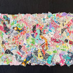 May include: A colorful patchwork quilt made from scraps of fabric in various patterns and colors. The quilt is frayed and has a rustic, handmade look.