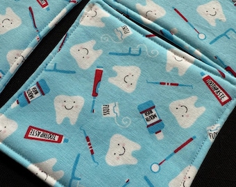 May include: Four blue fabric coasters with a white border. The coasters feature a repeating pattern of white teeth, toothbrushes, floss, and toothpaste tubes. The text on the coasters reads "Toothpaste", "Floss", "Mouth Wash", and "Toothpaste".