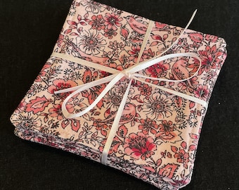 May include: Set of pink and white fabric coasters with a floral and bird pattern. The coasters are tied together with a white ribbon.