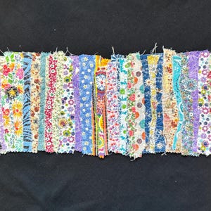 May include: A colorful fabric strip quilt with various floral patterns in shades of blue, pink, yellow, and green. The fabric strips are sewn together to create a patchwork design.
