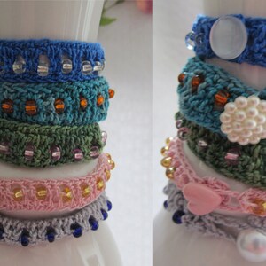 May include: A stack of crocheted bracelets with different colors and patterns, including blue, green, pink, and white. The bracelets are decorated with beads and buttons.