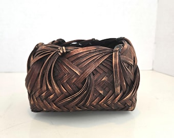 Cesta japonesa vintage de bambú tejido para Ikebana con un acabado oscuro ahumado y patrones de tejido esculturales.