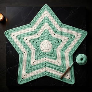 Peut inclure: Nappe en crochet en forme d'étoile, faite à la main, en vert menthe et crème. Le napperon présente un centre en spirale et un motif d'étoile à cinq branches. Une pelote de fil vert menthe et un crochet sont à côté.