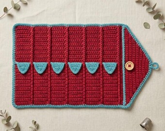 May include: A handmade, red crochet organizer with a turquoise trim and accents. The organizer features multiple pockets, a button closure, and a loop for hanging. The overall shape is rectangular with a pointed end.