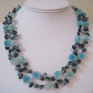 May include: A multi-strand necklace made of blue and black glass beads. The beads are faceted and have a sparkly finish.