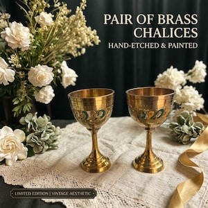 May include: A pair of brass chalices featuring hand-etched patterns and painted accents in green and yellow. The text on the image reads: PAIR OF BRASS CHALICES HAND-ETCHED & PAINTED. Each chalice has a wide bowl, a slender stem, and a circular base.