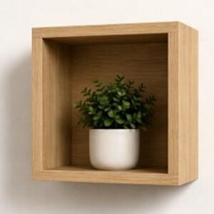 Peut inclure: Une étagère carrée en bois brun clair fixée à un mur blanc. À l'intérieur de l'étagère se trouve un petit pot en céramique blanche contenant une plante verte. L'étagère a un design simple et moderne.