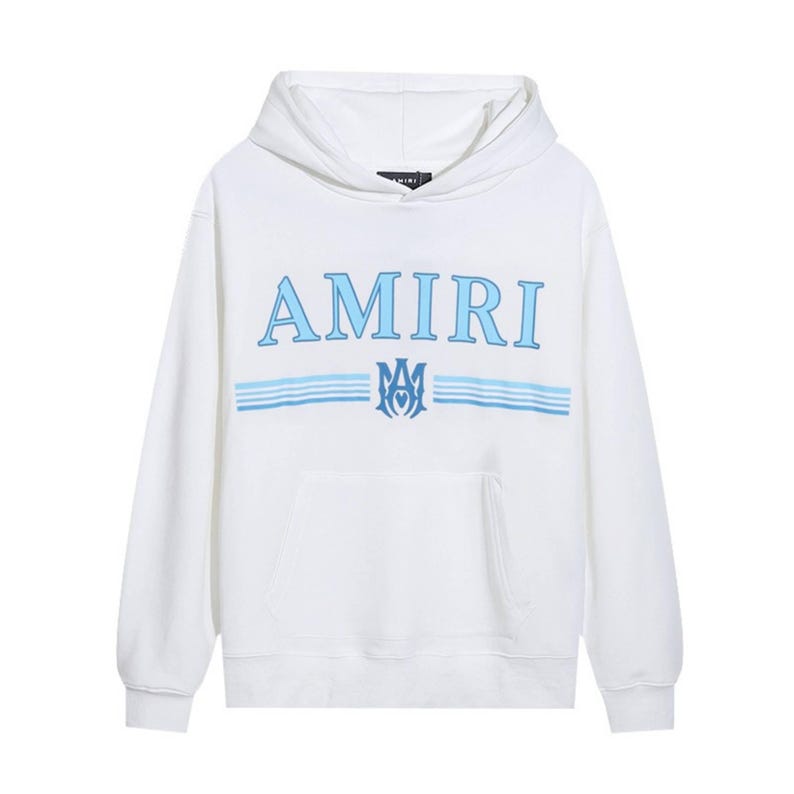 May include: White hoodie with the word "AMIRI" in light blue block letters across the chest. Below the word "AMIRI" are two light blue horizontal stripes and a light blue emblem. The hoodie has a front pocket and a hood.