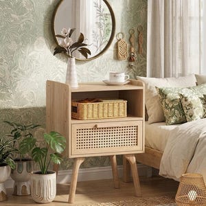 May include: A light wood nightstand with a woven drawer and a shelf. A woven basket sits on the shelf. The nightstand has a round mirror above it, and a bed with floral pillows is next to it. A vase with flowers is on the nightstand.