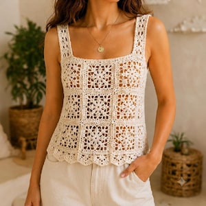 May include: A cream-colored sleeveless top crafted from crocheted square motifs featuring a central floral pattern. The garment has a square neckline, wide shoulder straps, and a scalloped hemline, paired with a gold pendant necklace on a thin chain.