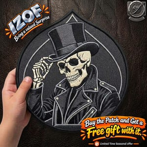 May include: A circular embroidered patch featuring a skeleton wearing a black top hat and a black leather jacket. The skeleton is depicted in a light cream color with dark shading, set against a dark gray circular background with a thin white border.