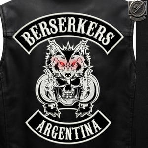 May include: A black leather vest featuring a large embroidered patch on the back. The patch displays a wolf head above a skull with curved tusks, flanked by two curved banners. The top banner reads BERSERKERS and the bottom reads ARGENTINA.