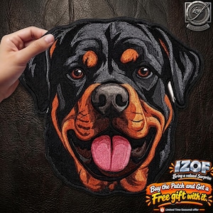 May include: An embroidered patch featuring the head of a Rottweiler dog with black and tan fur, brown eyes, and an open mouth with a pink tongue visible. The patch has a black border and is shaped to follow the outline of the dog's head.