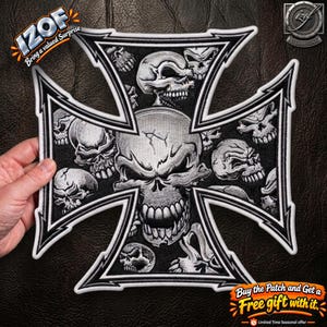 Könnte beinhalten: Ein schwarz-weiß bestickter Aufbügler in Form eines Eisernen Kreuzes mit einem großen zentralen Totenkopf mit Rissdetails, umgeben von mehreren kleineren Totenköpfen. Der Aufnäher hat einen dicken weißen Rand und feine schwarze Stickereien.