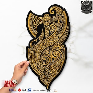 Könnte beinhalten: Ein schwarz-goldener Stickaufnäher mit einem detaillierten Streitaxt-Motiv. Der Axtkopf zeigt komplexe Knotenmuster, eine zentrale Figur mit Helm und ein kreisförmiges Baummotiv. Der Stiel und der umliegende Bereich sind mit fließenden, verzierten Schnörkeln gefüllt.