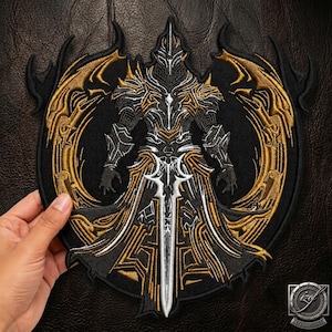 Puede incluir: Un parche bordado circular que presenta una figura central con armadura en hilo negro, plateado y dorado. La figura lleva un casco puntiagudo y una armadura ornamentada, sosteniendo una espada larga y afilada. El diseño está enmarcado por alas doradas.
