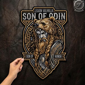 May include: A shield-shaped embroidered patch featuring a bearded figure wearing a bear headdress. The text reads LEGION VALHALLA, SON OF ODIN, and SON OF HONOR. The design uses gold, silver, and black thread with intricate geometric patterns.