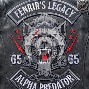 May include: A black leather jacket back panel featuring an embroidered patch with a snarling wolf head, red lightning bolts, and red stars. The text reads FENRIR'S LEGACY at the top, ALPHA PREDATOR at the bottom, and the number 65 on both sides.