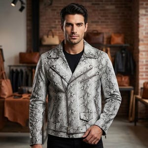 May include: A grey and white snakeskin print motorcycle jacket with a notched lapel, silver-tone metal zippers, a front belt with a buckle, and a small flap pocket. The jacket is worn over a plain black shirt, featuring long sleeves and a fitted cut.