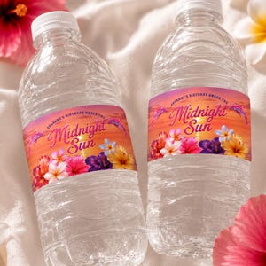 May include: Two clear plastic water bottles with custom labels featuring a sunset gradient background, tropical hibiscus flowers, and the text "Susanne's Birthday Under The Midnight Sun" in a cursive font, accented by small pink dolphin illustrations.