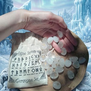 May include: A set of clear, polished gemstone rune stones, each marked with a gold-colored symbol. The stones are presented with a beige fabric drawstring pouch featuring the printed text Rune Stones Gemstone Set and a list of runic symbols.