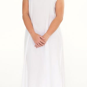 May include: A sleeveless white nightdress featuring a square neckline with delicate lace trim and intricate embroidery details. The garment is a solid white colour, falling to a mid-calf length with a loose, comfortable fit and simple hemline.