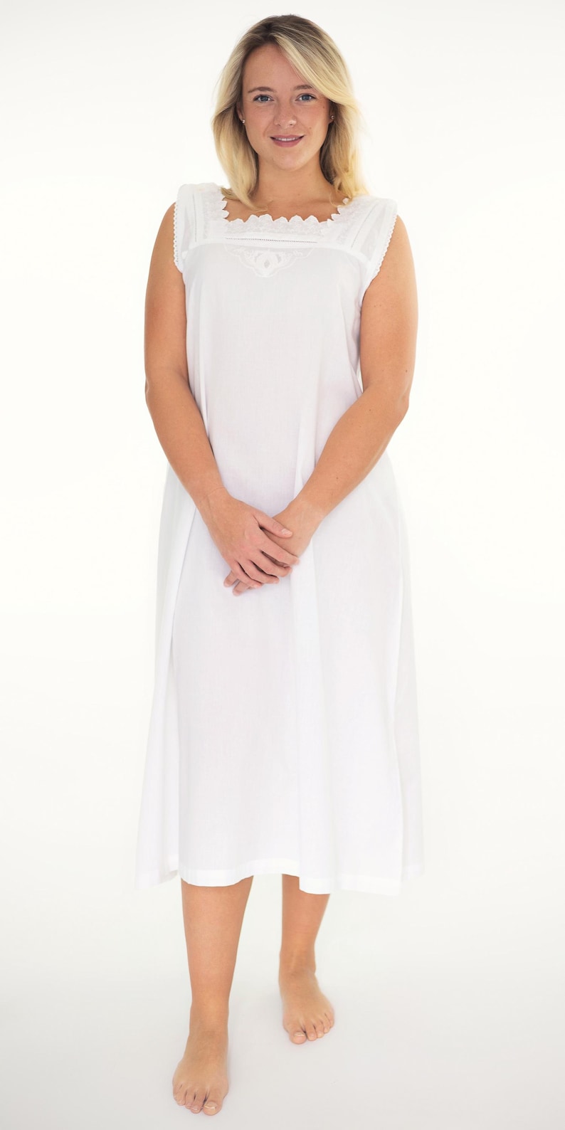 May include: A sleeveless white nightdress featuring a square neckline with delicate lace trim and intricate embroidery details. The garment is a solid white colour, falling to a mid-calf length with a loose, comfortable fit and simple hemline.