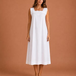 May include: A sleeveless white nightdress featuring a square neckline with scalloped lace trim and vertical pintuck detailing on the bodice. The garment has a loose, flowing silhouette that extends to the mid-calf, crafted from a solid white fabric.