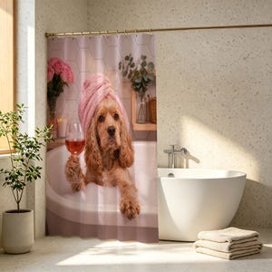 May include: A shower curtain featuring a golden-brown spaniel dog sitting in a bubble bath, wearing a pink towel wrapped around its head, and holding a glass of rose wine. The background shows a bathroom with pink hexagonal wall tiles.
