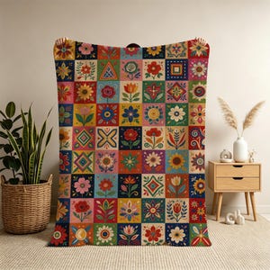 May include: A rectangular throw blanket featuring a grid of colourful squares, each decorated with distinct floral and geometric patterns in shades of red, blue, yellow, green, and pink. The design consists of repeating botanical motifs.