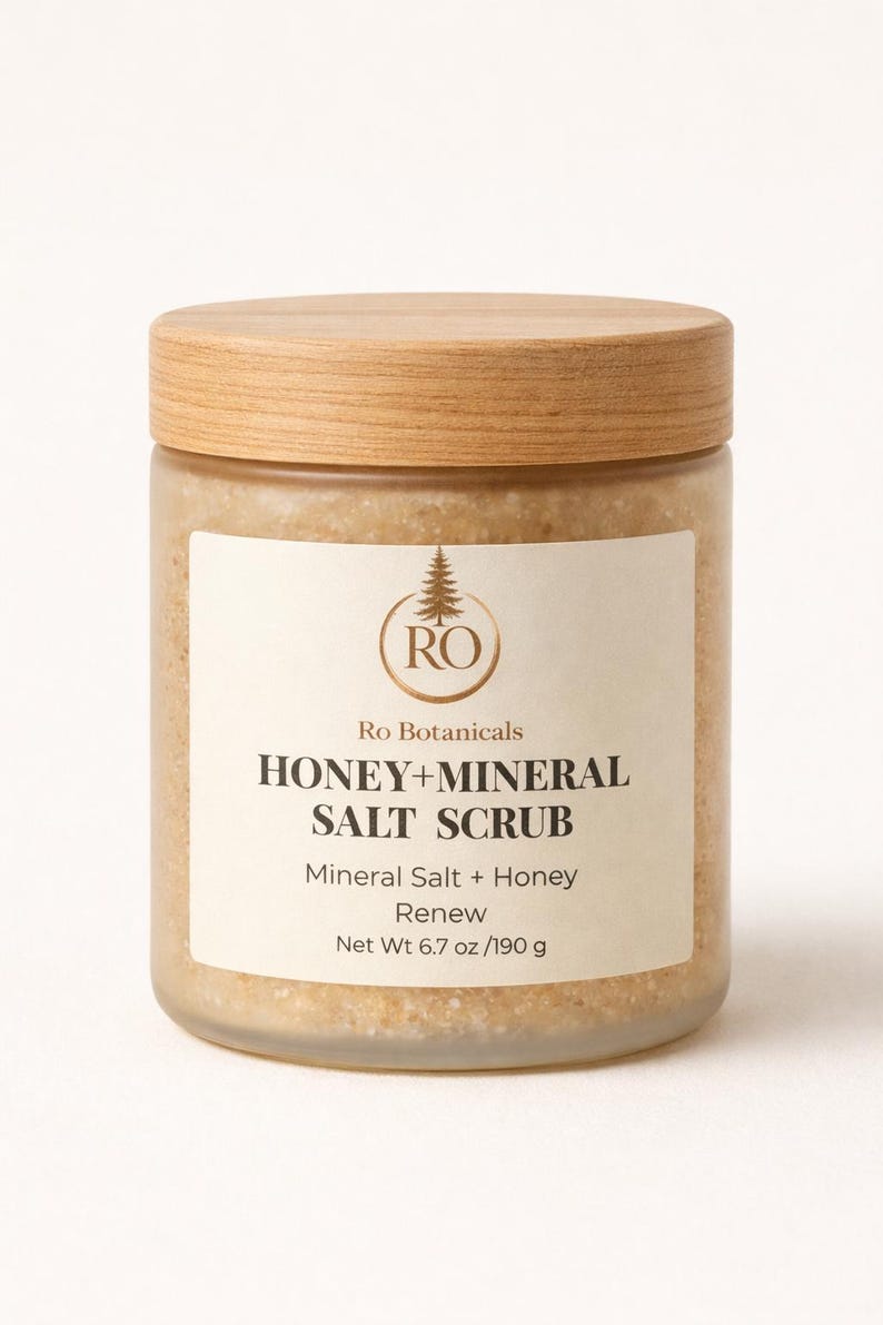 Pu&ograve; includere: Un barattolo di vetro con coperchio in legno contiene uno scrub al miele e sale minerale. L'etichetta recita "HONEY+MINERAL SALT SCRUB" e "Net Wt 190 g". Il barattolo contiene uno scrub marrone chiaro.